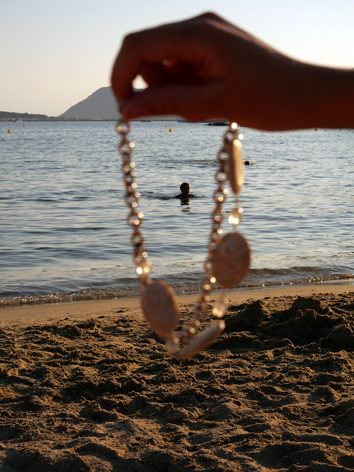 Photo d'une main tenant un collier avec une vue sur une plage et la mer