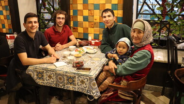 Photographie de Baptiste et Tanguy, co-fondateurs de Kashgar Artisananat, attablés avec une artisane partenaire au Kirghizistan, ainsi que son fils et son petit-fils