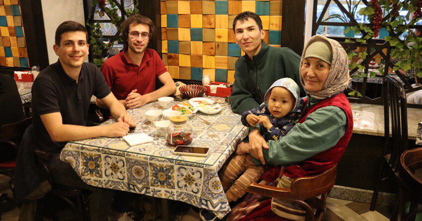 Photographie de Baptiste et Tanguy, co-fondateurs de Kashgar Artisananat, attablés avec une artisane partenaire au Kirghizistan, ainsi que son fils et son petit-fils